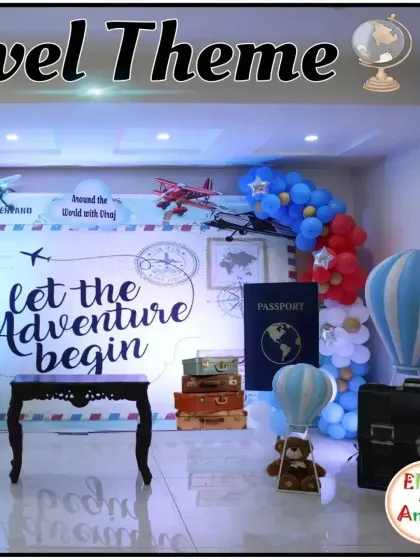A 'Let the Adventure Begin' travel-themed party. This setup includes a world map backdrop, vintage suitcases, and a hot air balloon prop.