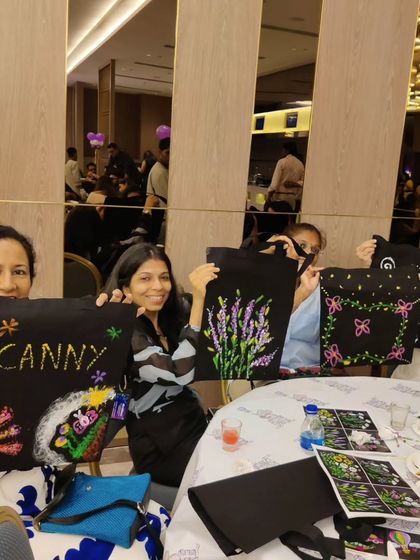Guests at the baby shower hold up their custom-painted tote bags, featuring personalized messages and designs for the mom-to-be.