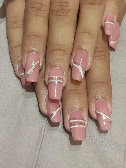 A modern and minimalist design with clean white and silver glitter lines over a dusty rose base. The lines are placed strategically for a chic, geometric effect on square-shaped nails.