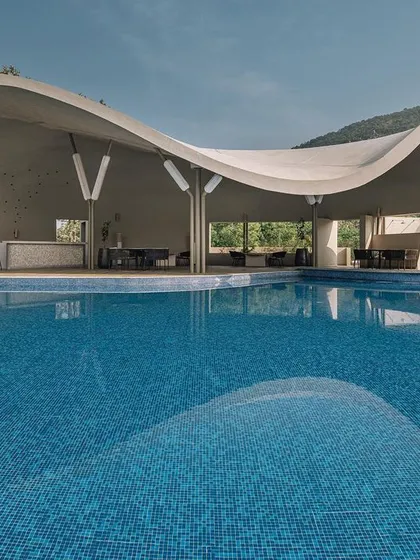 The same Aqua Pool & Spa project seen in daylight, where its sweeping, fluid form and parametric ferrocement roof are fully visible. The design captures panoramic views of the Nandi Hills, creating a seamless connection between the built environment and the vast outdoors.