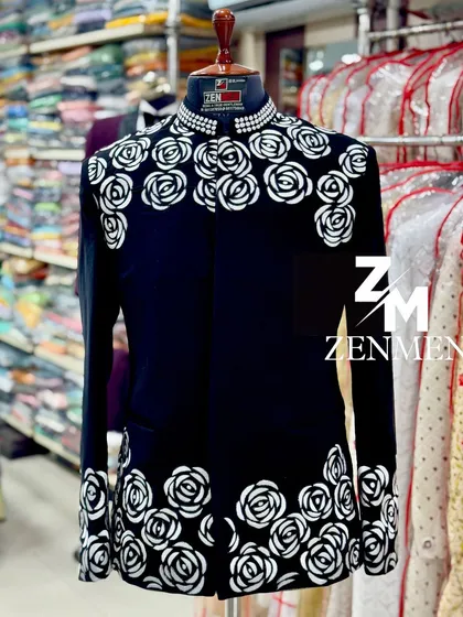 A bold black Jodhpuri suit with a striking white rose pattern and a pearl-studded collar. This is a high-fashion piece for a man who wants to make an artistic statement.