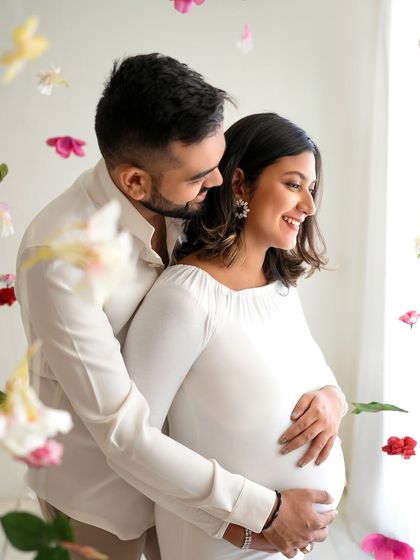 A close-up shot of the couple sharing a happy moment. The falling flowers add a beautiful, soft texture to this candid and loving portrait.