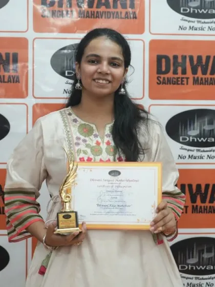 An adult student proudly holds her certificate and trophy.
