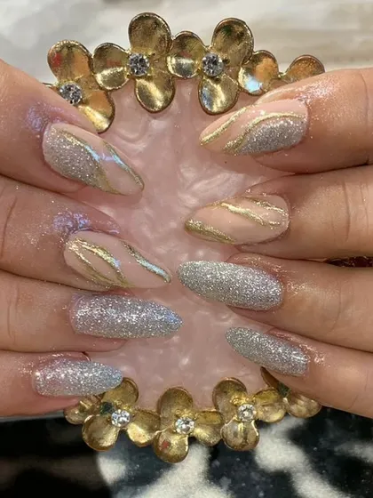 A sparkling combination of full silver glitter nails and nude nails with elegant gold and silver waves.