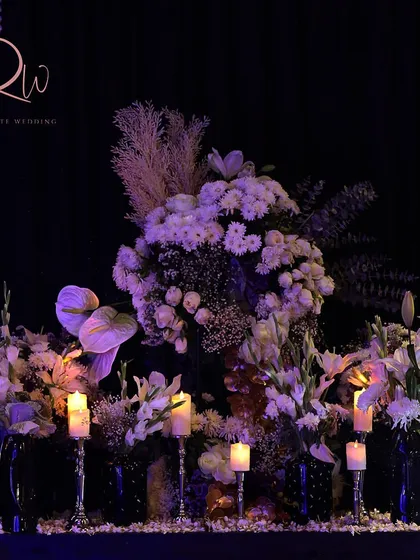 A floral arrangement for a cocktail night in Udaipur, featuring white flowers and candles on a silver stand.