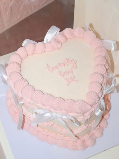 From another angle, you can see the layers of detail in this pink and white heart-shaped vintage cake, ready to make a birthday wish come true.