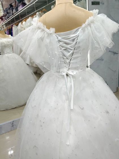 The back of the fairytale tulle gown, showing the classic corset lacing that allows for a perfectly sculpted fit. The ruffled sleeves add a touch of whimsical charm.