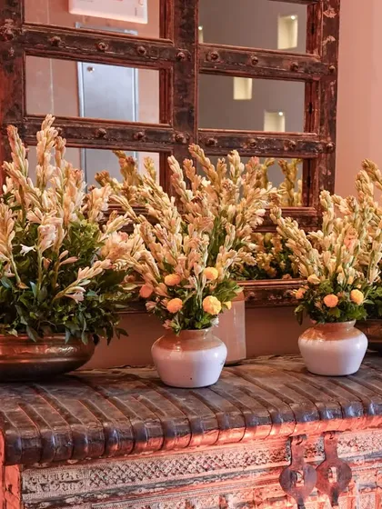The fragrance of Rajnigandha (tuberose) can instantly create a festive, ethnic feel. We used these beautiful flowers in brass and ceramic pots, placed on a rustic wooden chest, to style the entrance for a home celebration.