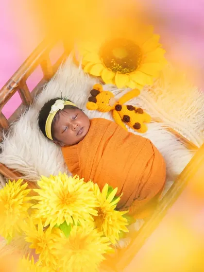 A dreamy shot of a newborn sleeping in a tiny bed, surrounded by sunflowers. The soft, hazy filter adds a magical and artistic touch to this sunny-themed photo.