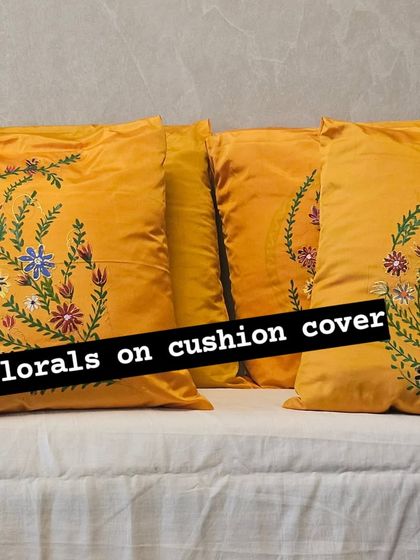 A full view of the set of four yellow silk cushion covers with hand-painted floral sprays. They look beautiful arranged together on a couch, creating a cohesive and cheerful look.
