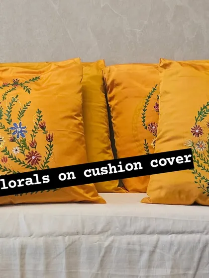 A full view of the set of four yellow silk cushion covers with hand-painted floral sprays. They look beautiful arranged together on a couch, creating a cohesive and cheerful look.