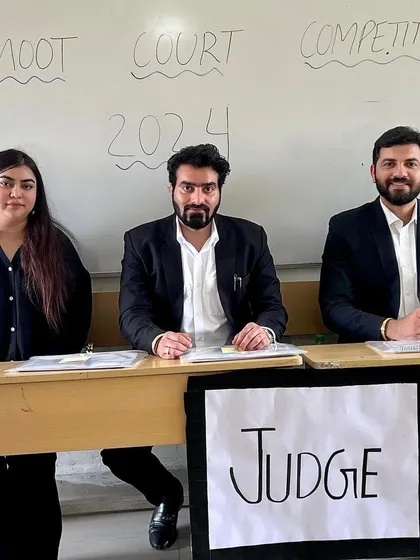 As a judge for the semi-finals of an Intra Moot Court Competition. The handwritten "Judge" sign shows the raw, authentic environment of these student-run events, where the passion for law is truly visible.