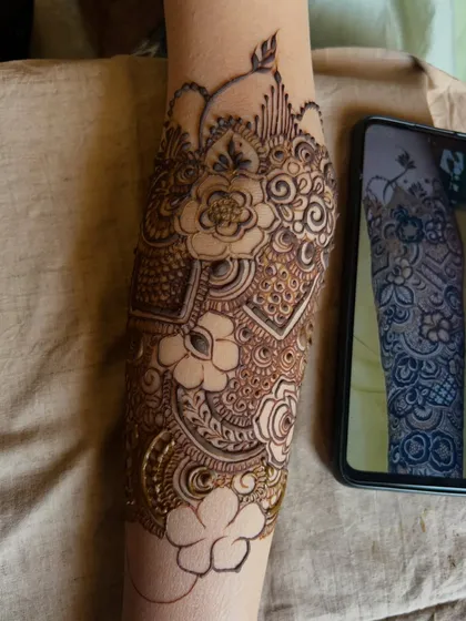 The full forearm design coming together, with the reference photo nearby to ensure every detail is perfect.