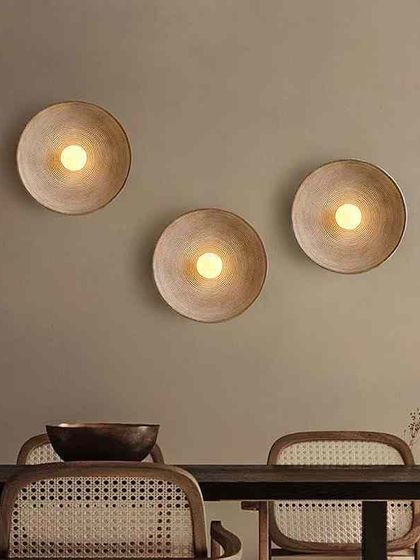 A set of three minimalist bowl sconces installed in a dining area. Using multiple sconces creates a beautiful rhythm and provides ample ambient light.