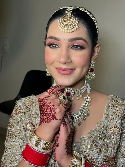 A radiant bridal portrait. The soft pink eyeshadow and nude pink lip create a fresh and modern feel, while the intricate jewelry adds a touch of tradition.