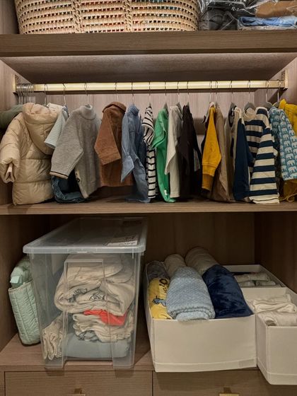 This child's closet combines hanging space for jackets with shelf storage for folded clothes and clear bins for out-of-season items.