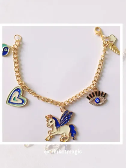 A close-up of a custom bracelet featuring a majestic winged unicorn, a heart, and an evil eye charm. The gold and blue enamel details make this piece truly stand out.