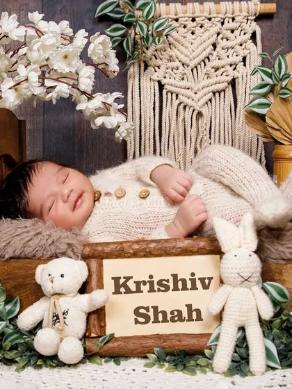 A personalized newborn setup for Krishiv Shah, featuring him sleeping in a rustic bed with boho decor.