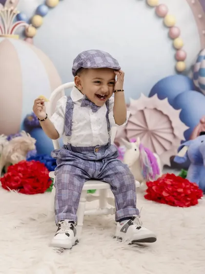 A laugh that could light up any room! This little boy enjoys his carnival-themed first birthday shoot, showcasing his joyful personality and dapper outfit.