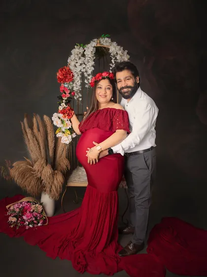 A beautiful couple's portrait during their maternity session. The rich red gown and floral accents create a romantic and vibrant look, celebrating their growing family.