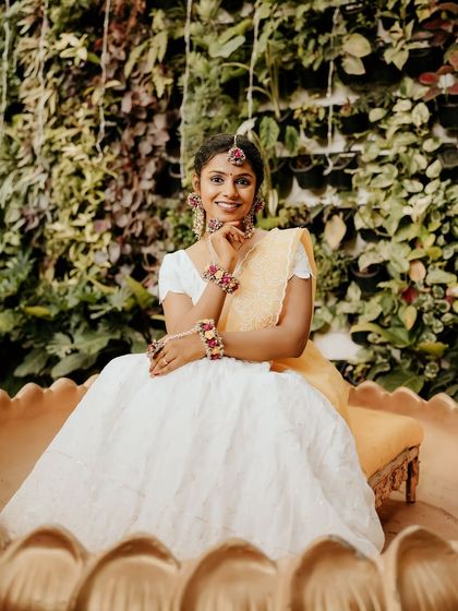A beautiful portrait of a bride in a white and yellow outfit for her Haldi ceremony.