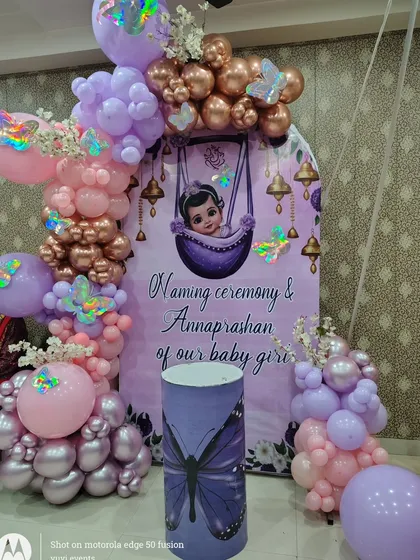 A beautiful setup for a joint Naming Ceremony and Annaprashan, with a purple and pink butterfly theme.