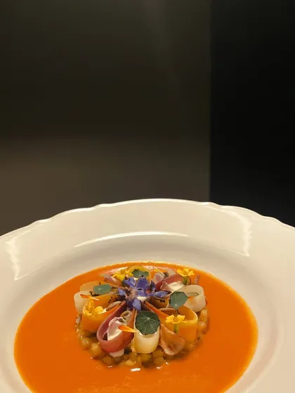 A vibrant vegetarian main course of pearl couscous cooked with Indian spices, served with confit topinambur and a velvety tomato shorba.
