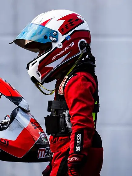 A driver stands next to his kart, contemplating the session ahead.