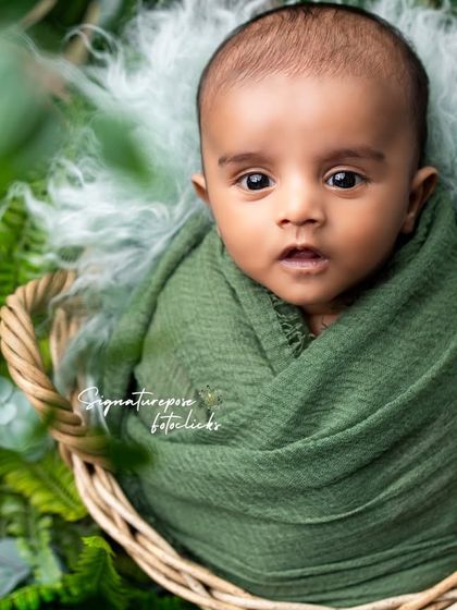 A duplicate of image 74, an alert and curious newborn in a nature-themed setup.
