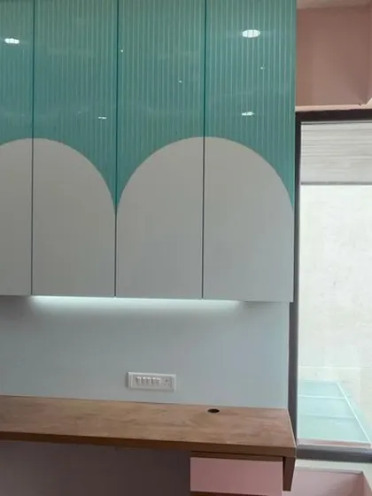 This image highlights the functional study area in the kids' room, featuring a wooden desk and overhead cabinets with a playful, curved design.