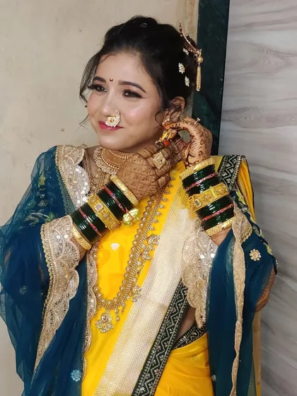 A candid moment of Urmila adjusting her earrings, showcasing the intricate details of her jewellery and the green glass bangles.