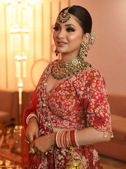 A vision in red. This bride pairs her traditional red lehenga with a heavy Kundan and green bead necklace set, complete with a matching maang tikka and oversized earrings.
