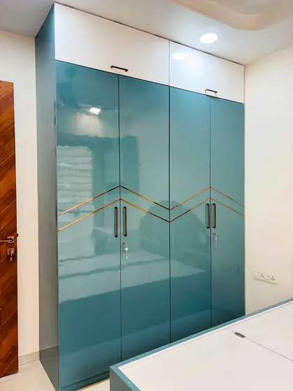 A different angle of the glossy teal wardrobe, showing how the light reflects off the surface, adding to the room's brightness.