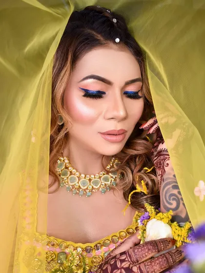 A dreamy shot through the yellow dupatta, highlighting the bold blue winged eyeliner.