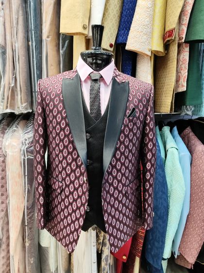 This designer suit features a unique patterned wine-colored jacket with a solid black waistcoat and lapels. It's a bold choice for a groom or party-goer who wants a distinctive look.