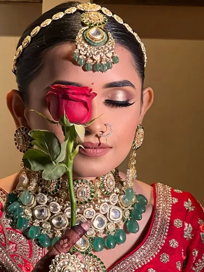 Forever starts with flawless. This artistic shot with a red rose highlights the bride's perfectly blended eyeshadow and classic red lip, a symbol of romance.