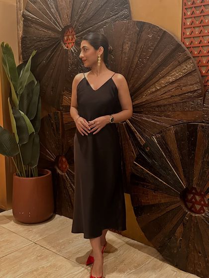 Posing against a wooden backdrop in my brown dress. This outfit is a reminder that life is happening now.