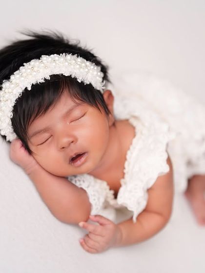 A peaceful sleeping pose in a delicate white lace outfit. The simplicity of the white-on-white setup is timeless and elegant.