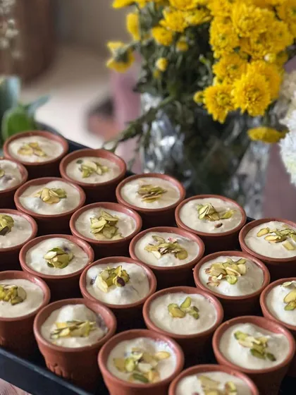 A tray of our delicious Phirni, served in individual terracotta bowls, ready for a festive gathering.