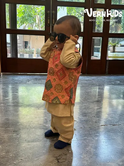 Putting on his shades, this little one is ready for the party in his peach printed Bundi set. A perfect blend of cute and cool.
