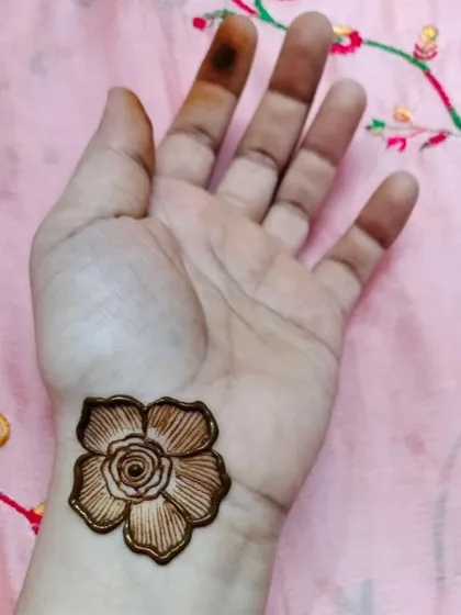 A single, beautifully detailed flower on the wrist. This is a perfect choice for someone trying henna for the first time or who wants a very simple design.