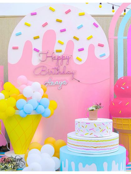 The birthday backdrop for an ice cream party, featuring a melting ice cream design with 3D sprinkles and a custom neon sign. The balloon-filled waffle cone adds a playful touch.