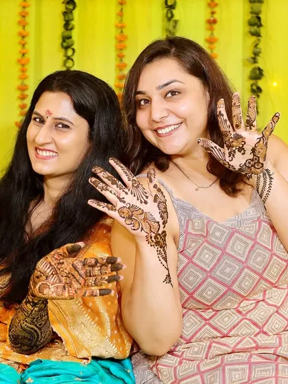 A happy moment between the bride and her friend, both showing off their Mehndi. It's a celebration for everyone.