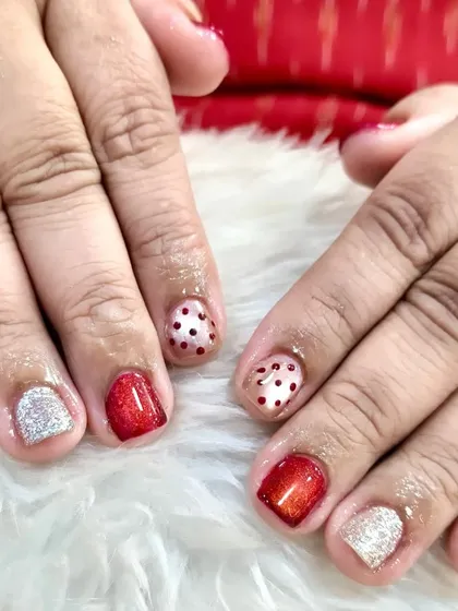 Small nails, big Christmas vibes. This shows that even on tiny nails, you can have a huge festive impact with cute reds, sparkles, and Christmas dots.