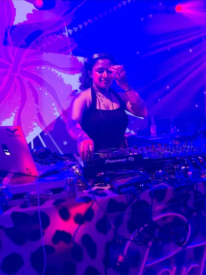 Mixing under cool blue and purple lights with psychedelic visuals in the background for a private event.