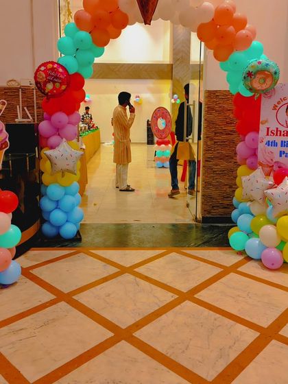 The entrance to the 'Candyland' party, featuring a colorful balloon arch and a large ice cream cone cutout to welcome the guests.