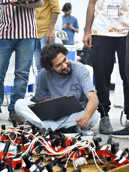 An engineer works on his laptop surrounded by drones, a typical scene at our workshop. The smiles and focus show the passion our team has for creating magic in the sky.