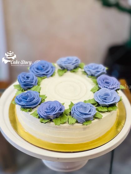 A simple and elegant floral cake. The white cake is adorned with a ring of beautiful, hand-piped purple roses.
