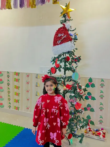 A student poses proudly in front of the fully decorated Christmas tree.