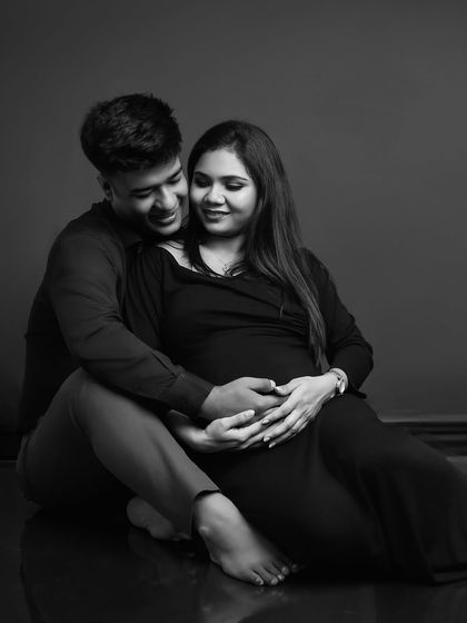 A moment of shared joy. This seated pose in black and white feels cozy and intimate, capturing the couple's happiness as they await their new arrival.